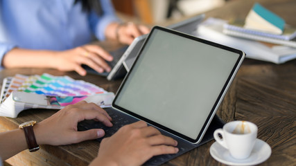 Cropped shot of young designer team focusing on their work on wooden desk