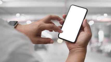 Close up view of businessman using blank screen smartphone in car parking
