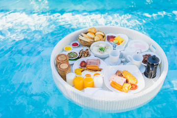 Floating breakfast set in tray with fried egg omelette sausage ham bread fruit milk juice coffee