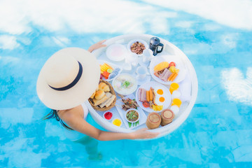 Portrait beautiful young asian woman happy smile with floating breakfast in tray on swimming pool