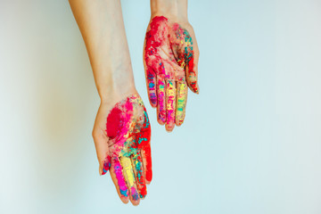 Concept of Holi, Indian festival of colors. Image of women's hands on white background, close-up....