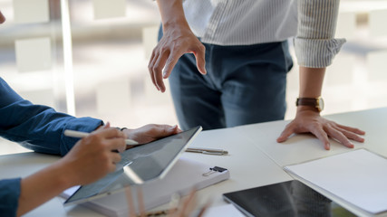 Cropped shot of businesspeople consulting on their project with digital tablet and document file