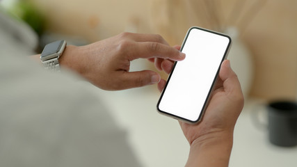 Close up view of male designer using blank screen smartphone while relaxed from work