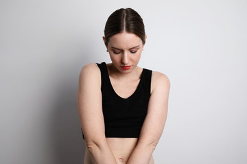 Young woman wearing casual black underwear looking down and posing in the studio. 