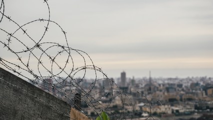 Cerca de alambres de puas para seguridad sobre un muro con la ciudad de lima de fondo