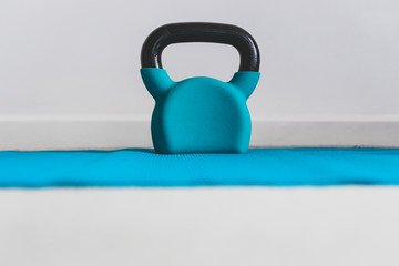 Naklejka na ściany i meble home gym concept, blue yoga mat with kettlebell shot at shallow depth of field from low perspective