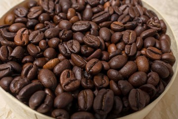 coffee grains in a round wooden jar on a background of crumpled parchment