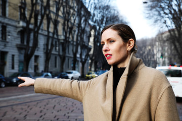 Young woman grabbing taxi in the city center.