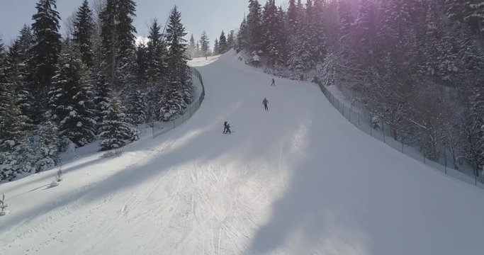 Aerial shot slowly goes up shots skiers on the slope and then goes on the breathtaking landscape view in Bakuriani ski resort
