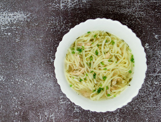 Noodle soup in a bowl on a dark background. Top view, flat lay.