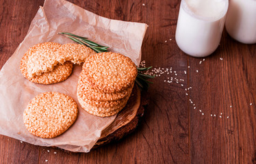 Round sesame cookies with milk and juice on the table.