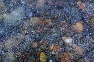 Obraz na płótnie Canvas texture multicolored pebbles covered with transparent ice river ice