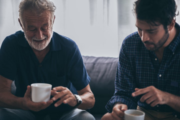 Father-son bonding. Cheerful young man drinking coffee together with him