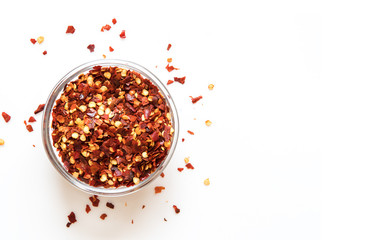 crushed red chili pepper in glass bowl.  Top View on white background