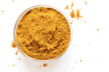 Curry Powder in glass bowl shows partial on white background.  Asian Cuisine with oriental spices. Top View