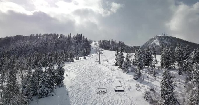 Aerial drone shot of a ski chair lift movement and beautiful snowy landscape 