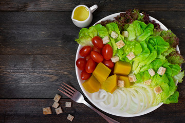 Fresh salad with green oak in white dish on wooden table.
