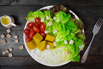 Fresh salad with green oak in white dish on wooden table.