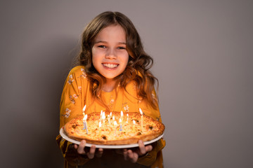 teen girl holding pizza with candles is smiling