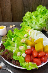 Fresh salad with green oak in white dish on wooden table.