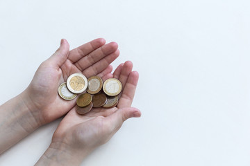 A handful of coins in the palm of hands. Euro coins on a white background