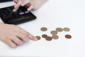 Cute little child girl counts on a calculator. The child saves money on the concept of the future