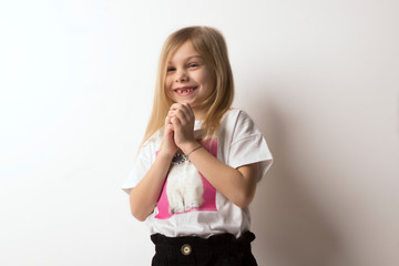 portrait to the waist of little blonde girl of six seven years old in a in a white print t-shirt...