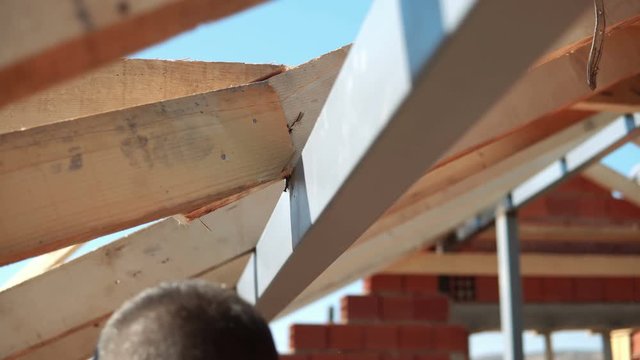 construction roofer carpenter worker nailing wood board with hammer on roof installation work