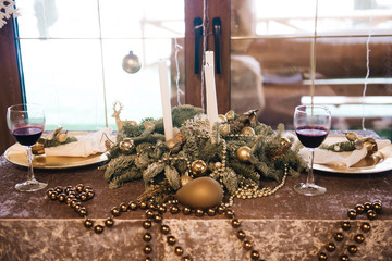 Beautiful serving table with Golden plates decorated with spruce and wine glasses. The concept of Christmas