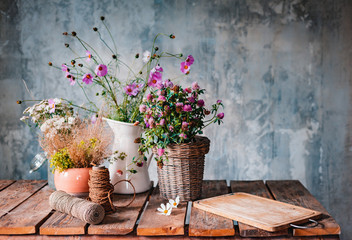 Beautiful bouquets of wildflowers on a wooden table on a cold concrete wall background.
