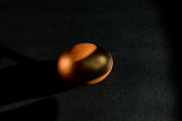 Golden egg on black background . Minimal style backdrop with copy space.
