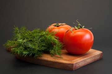 Tomatoes are red. Fresh dill. On a black background