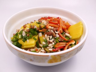 Photo of a large white bowl with salad ingredients - sliced mango. bell pepper, green onions / scallions. chopped peanuts. Healthy salad photo.