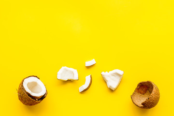 Coconuts frame - halfs and scattered pieces - on yellow background top-down copy space