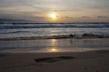 Golden dawn at sea, waves running onto the sand