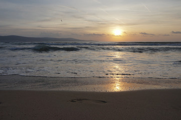 Golden dawn at sea, waves running onto the sand