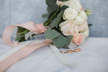 wedding gold rings on a table with a bouquet
