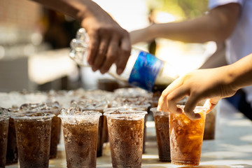 Workers are distribute free beverages or black water to people,.soft drink is poured into a glass of plastic,beverages for children and tourists,cold drinks to quench hot and thirsty at service point