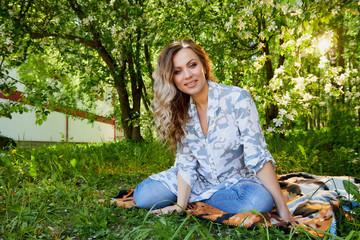 Girl sitting on the grass in the park with flowering Apple trees in a spring time