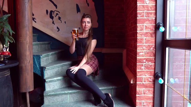 girl in mini skirt sitting on stairs drinking beer