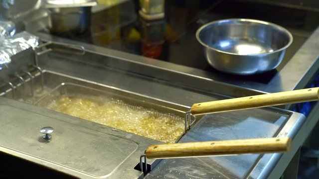boiling oil in deep fryer chicken wings. Kitchen.