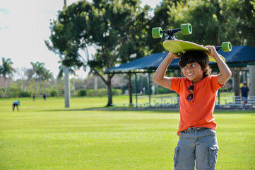 cuban indian boy skateboard on head sideways smile glasses on shirt park green grass vision freedom 