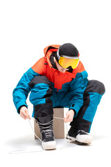 Portrait young man in sportswear with snowboard fastens boots isolated white background