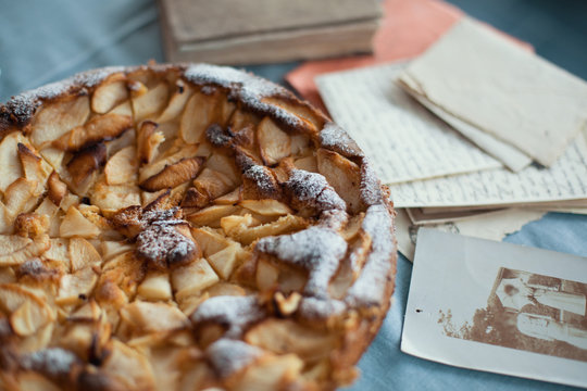 Rustic, traditional, apple pie on the blue table, old photos, letters and book in the background