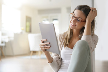 Woman at home relaxing and websurfing with digital tablet