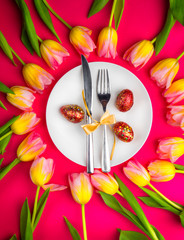 Easter table cutlery with tulips and eggs on red background