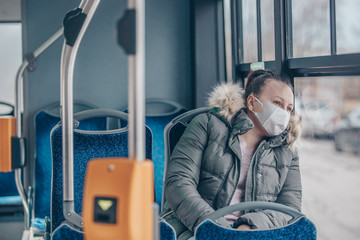 Coronavirus covid 2019 woman with respiratory mask traveling in the public transport by bus,...