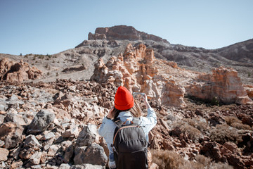 Young traveler in red hat with backpack photographing on phone rocky landscape while travel on the desert valley on Tenerife island © rh2010