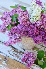 Lilac flowers in basket on a wooden background