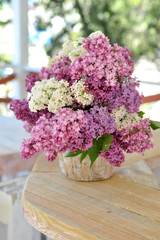 Lilac flowers in basket on a wooden background